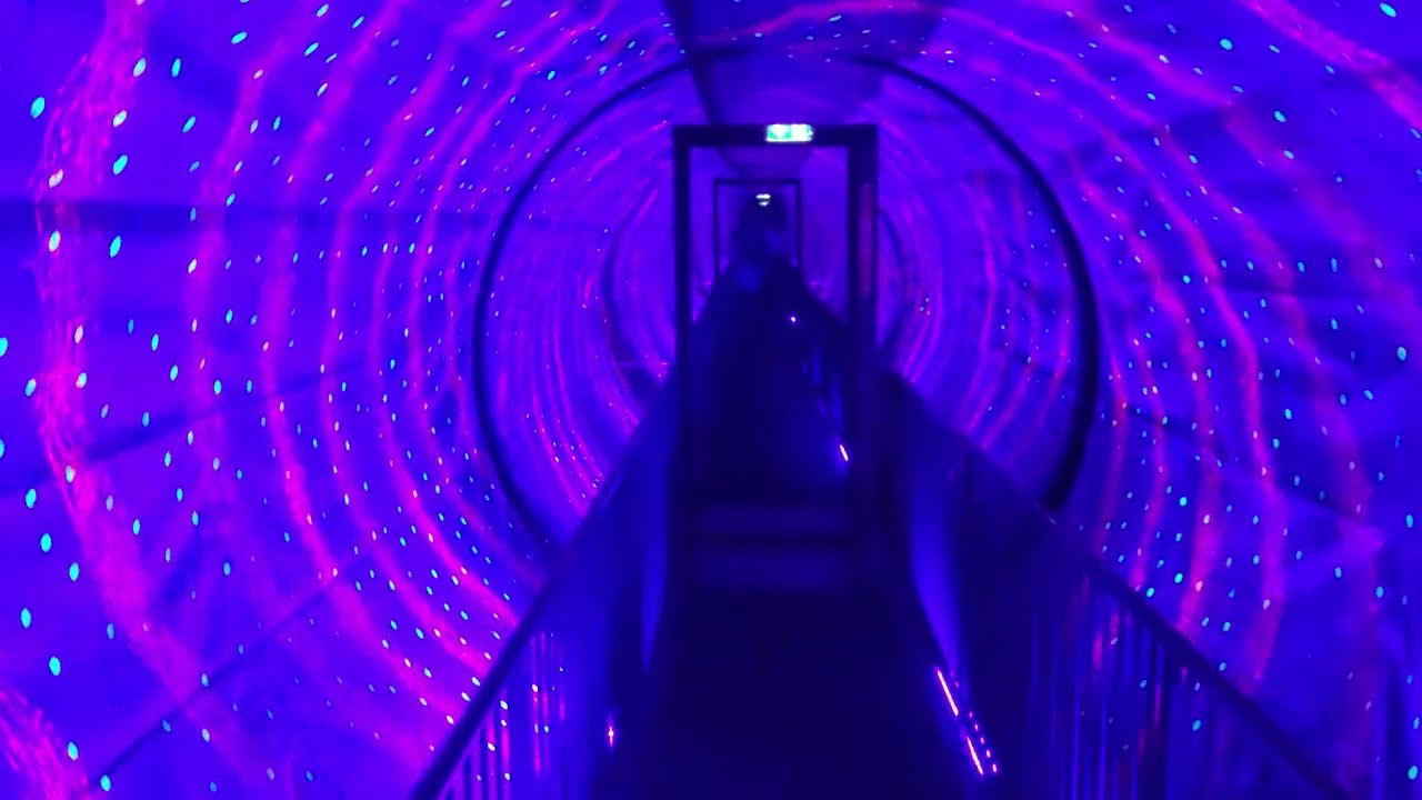 Visitor walking through a spinning vortex tunnel installation at the Museum of Illusions San Diego